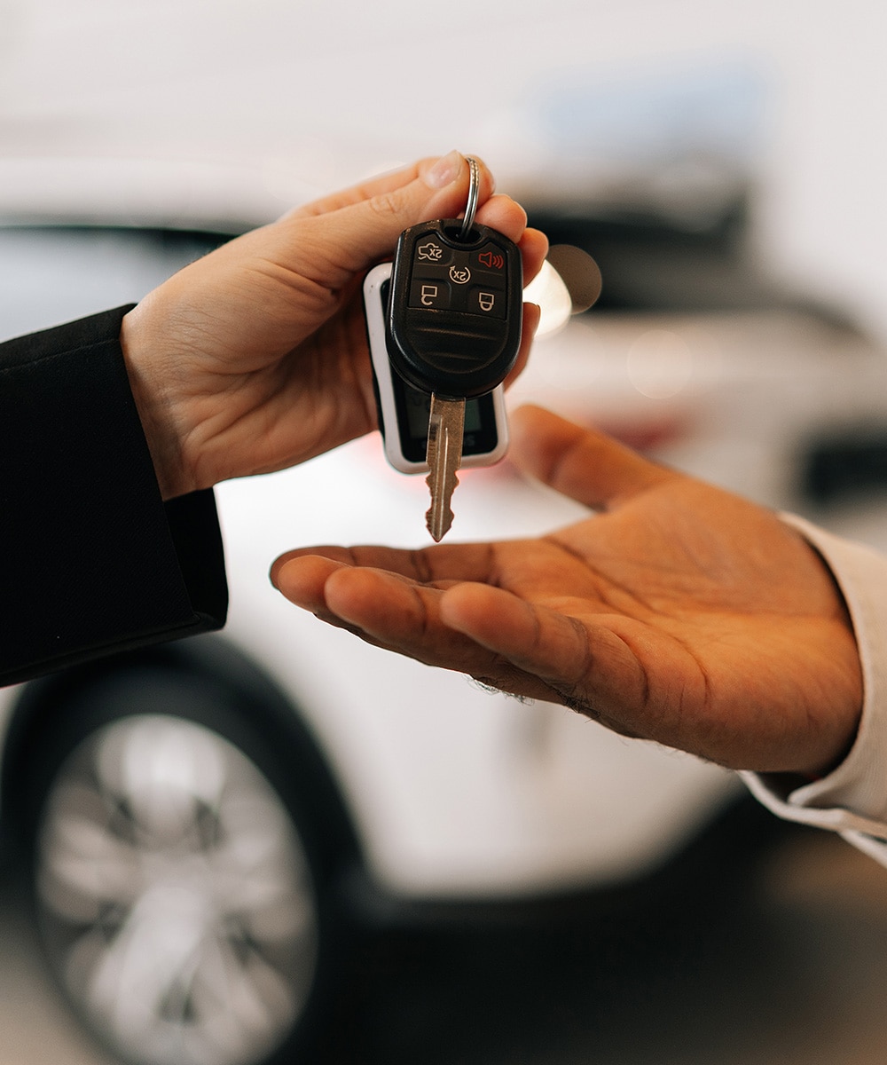 Mano recibiendo y entregando llaves de un carro nuevo
